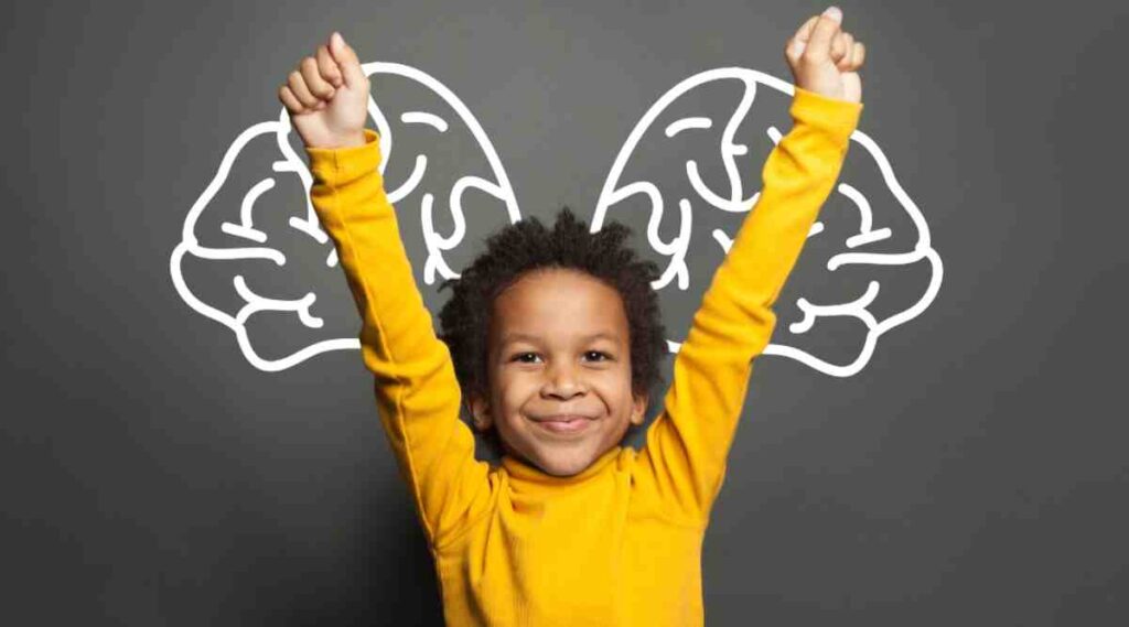 A child in a bright yellow sweater raises both arms triumphantly