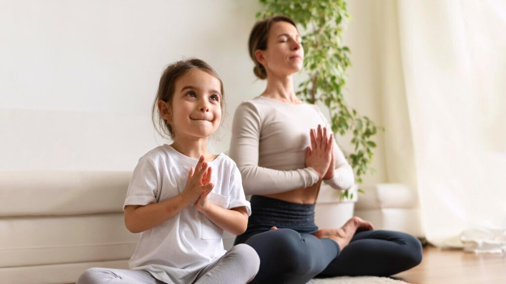 A child and an adult practice yoga together in a serene indoor setting
