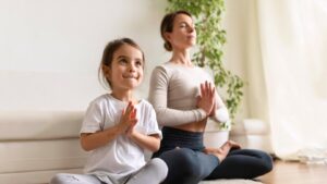 A child and an adult practice yoga together in a serene indoor setting