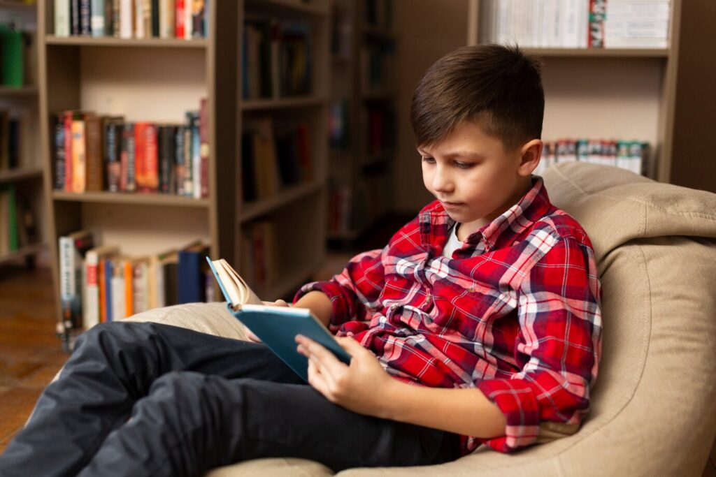 A child in a red plaid shirt sits comfortably on a beanbag