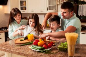 A family of four preparing vegetables together in a kitchen.