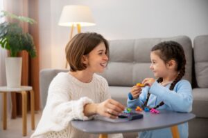A mother and daughter play with toys at a table in a cosy living room.